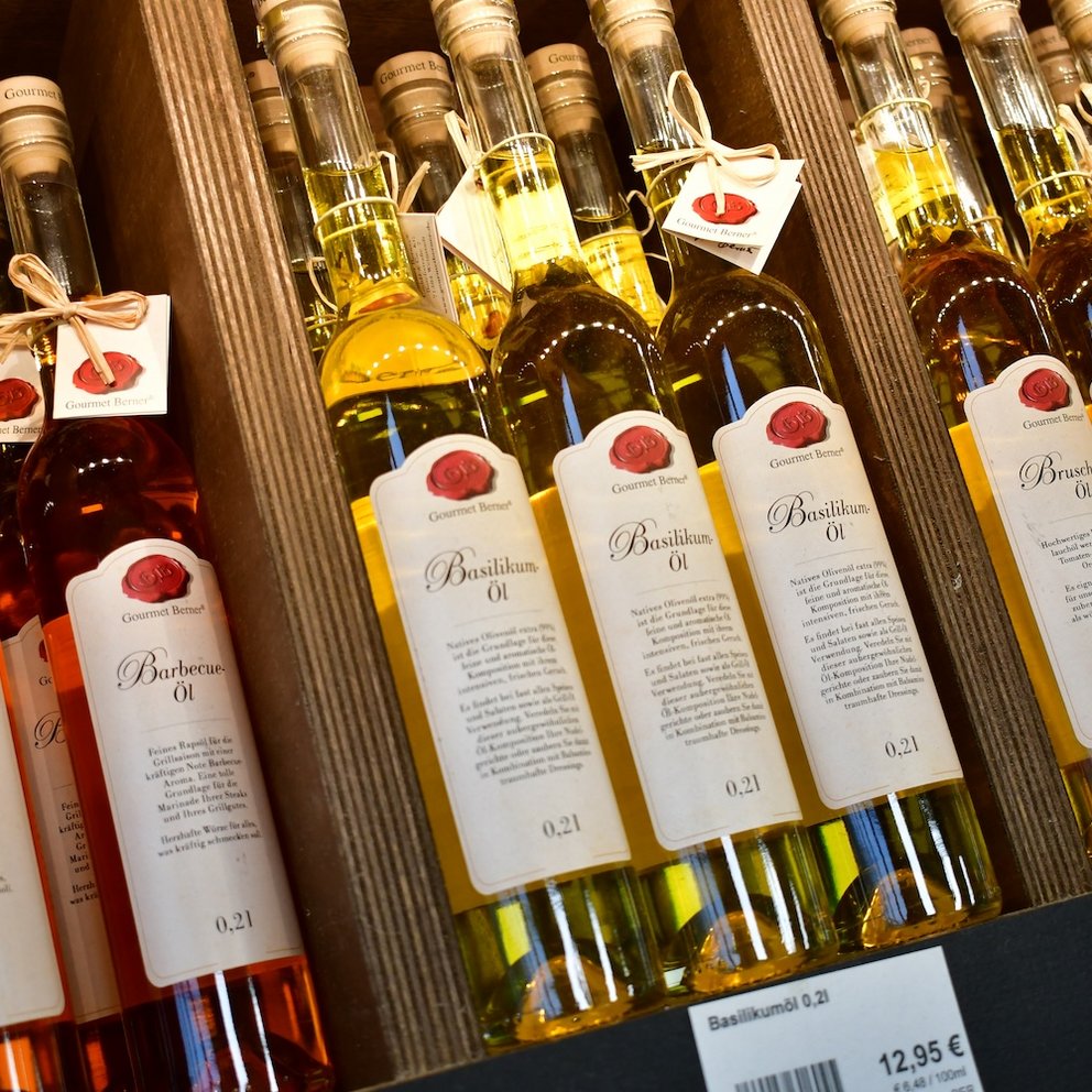 verschiedene Flaschen Öl in einem Holzregal