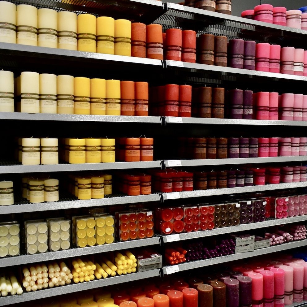 Regal mit verschiedenen Kerzen angeordnet in Regenbogen-Farben