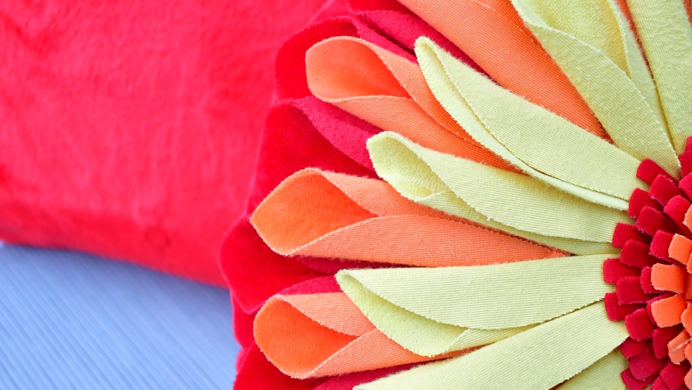 Ein Kissen in Blumenform vor einem einfarbigen roten Kissen