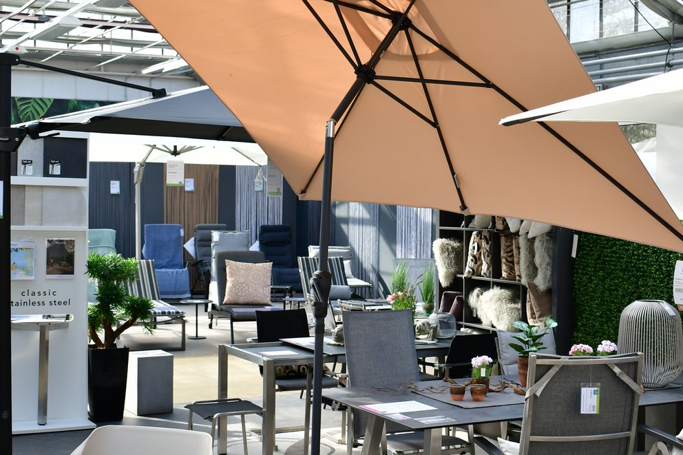 Ein Sonnenschirm neben zahlreichen Gartenmöbeln.