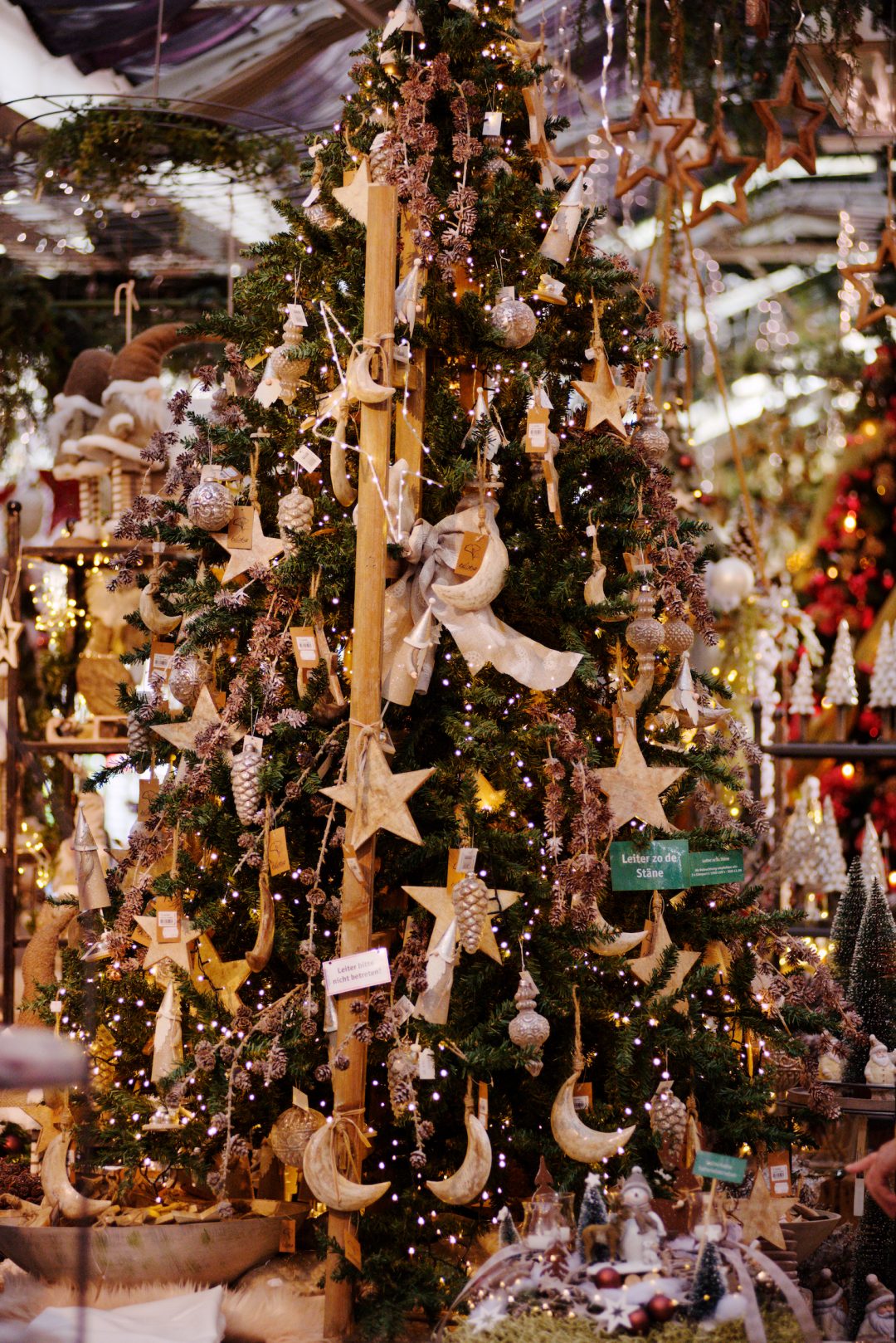 Dekorierter Weihnachtsbaum mit dem Namen Leiter zu den Sternen. Dekoriert mit Holzsternen, Schleifen und einer großen Holzleiter.
