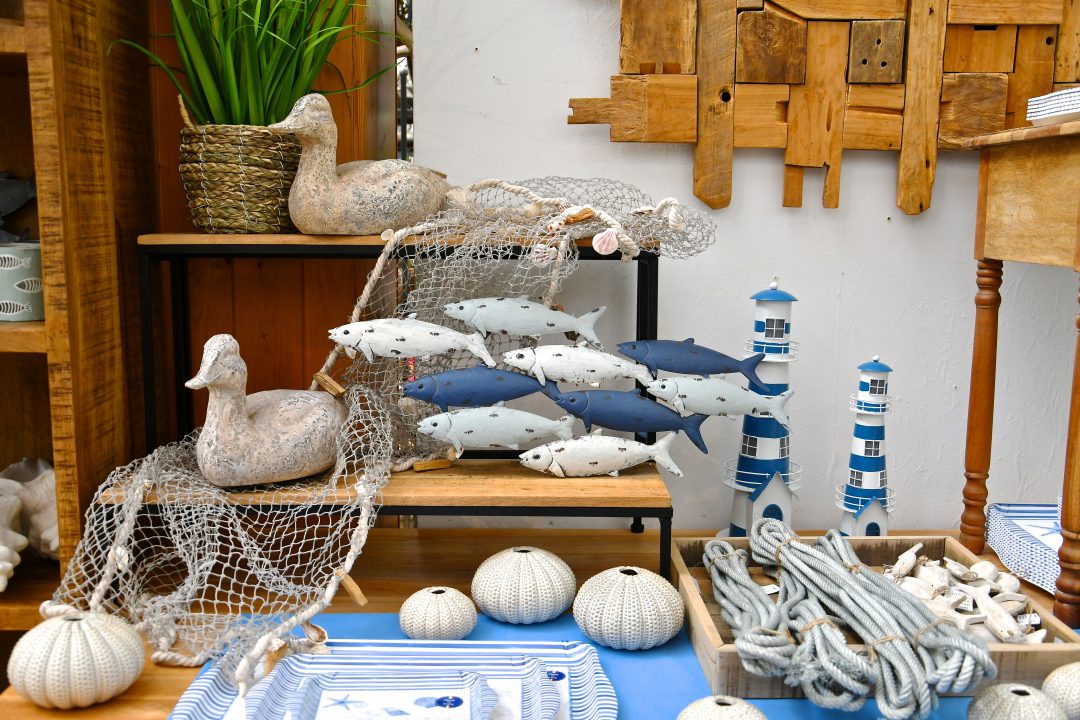 Maritime Dekoration. Man sieht Leuchttürme, ein Fischernetz mit Fischen und daneben Enten die Sommerfeeling widerspiegeln