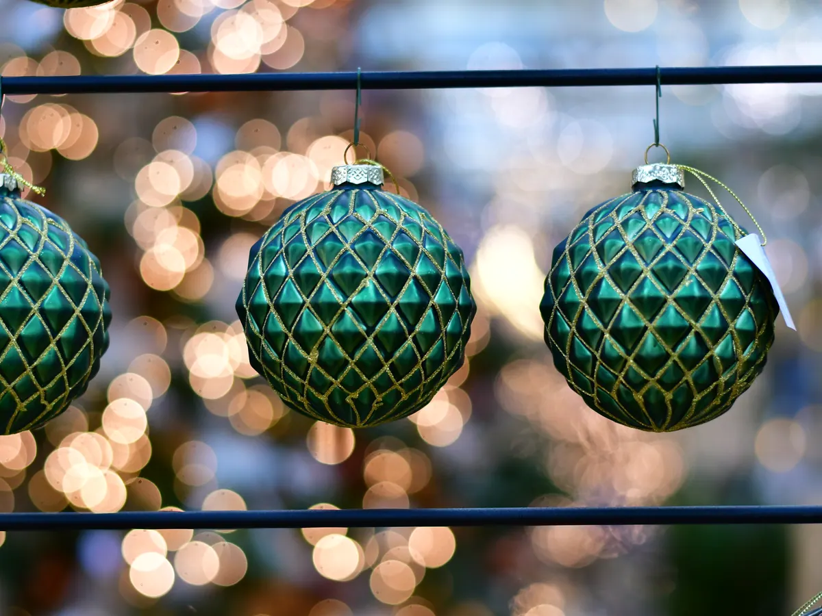 Grüne Weihnachtskugeln mit Rautenmuster vor Lichtern