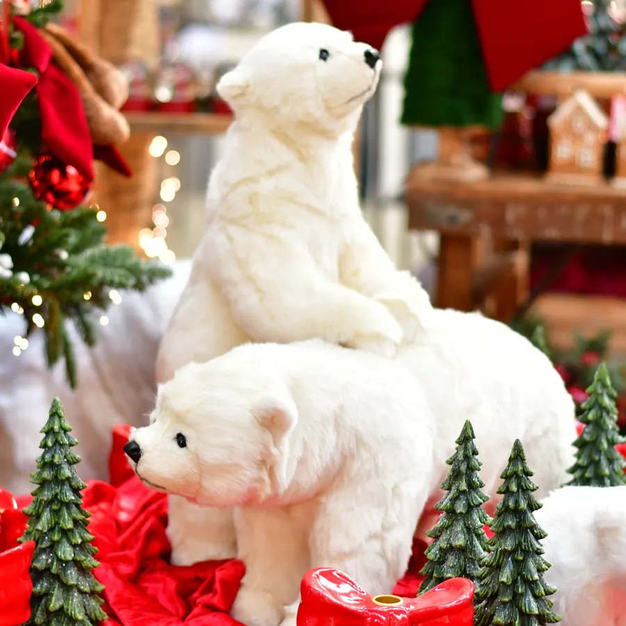 Plüsch-Eisbären zwischen roten Geschenken und kleinen Tannen