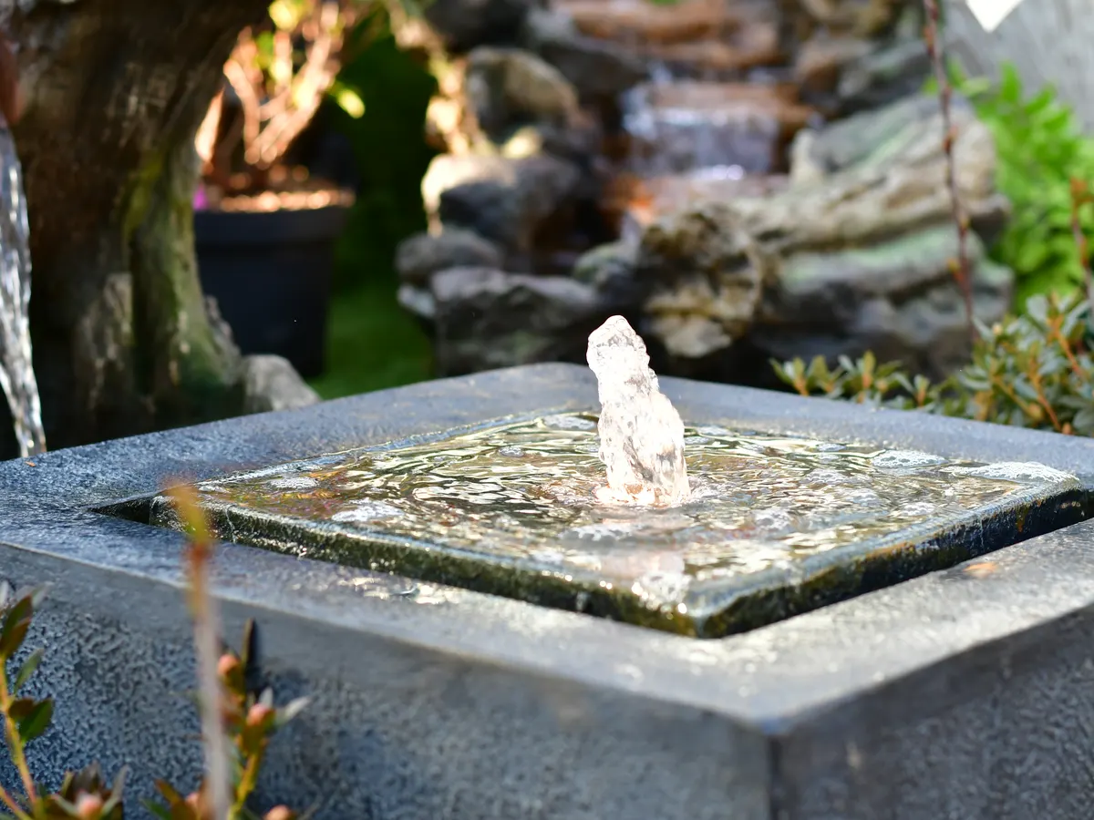 Quellstein mit sprudelndem Wasser auf einer Steinplatte
