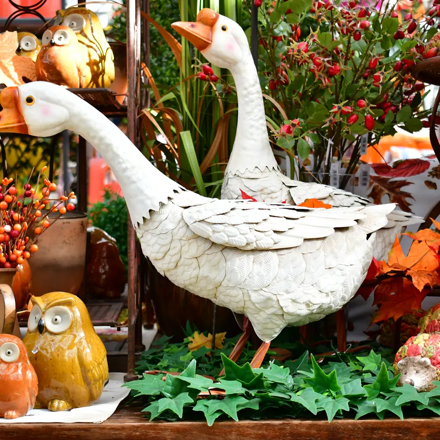 Große Gänse-Figuren zwischen herbstlichen Seidenblumen