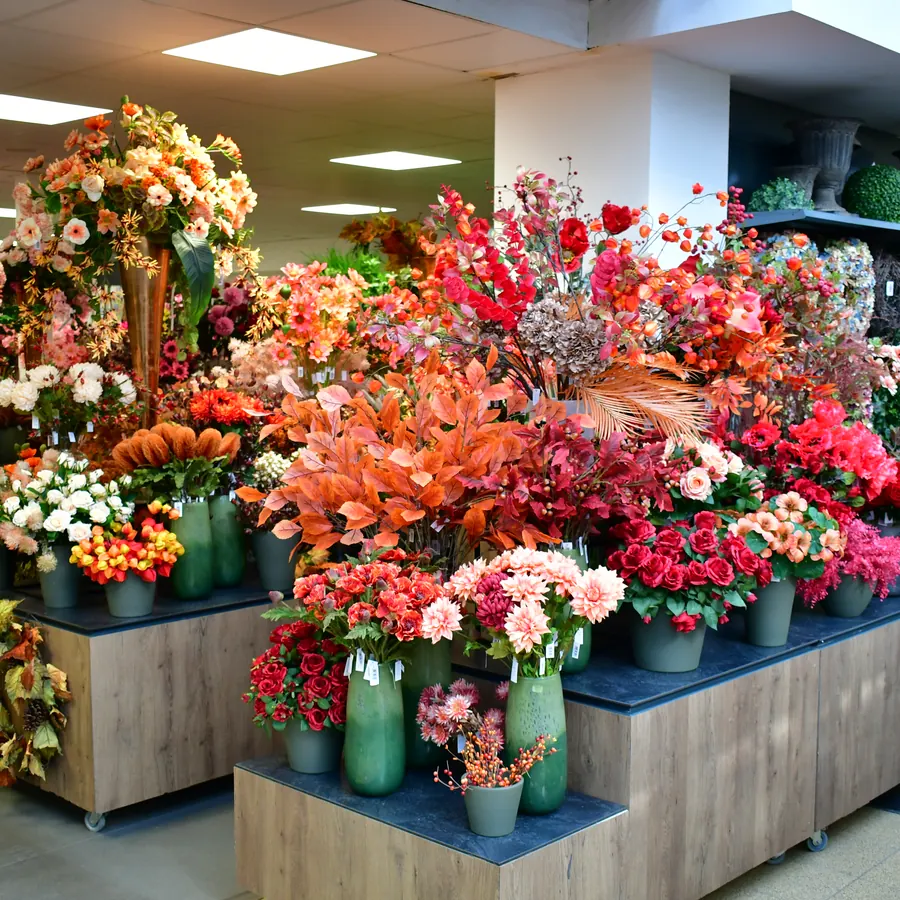 Tische voller Seidenblumen in Herbstfarben in der Boutique