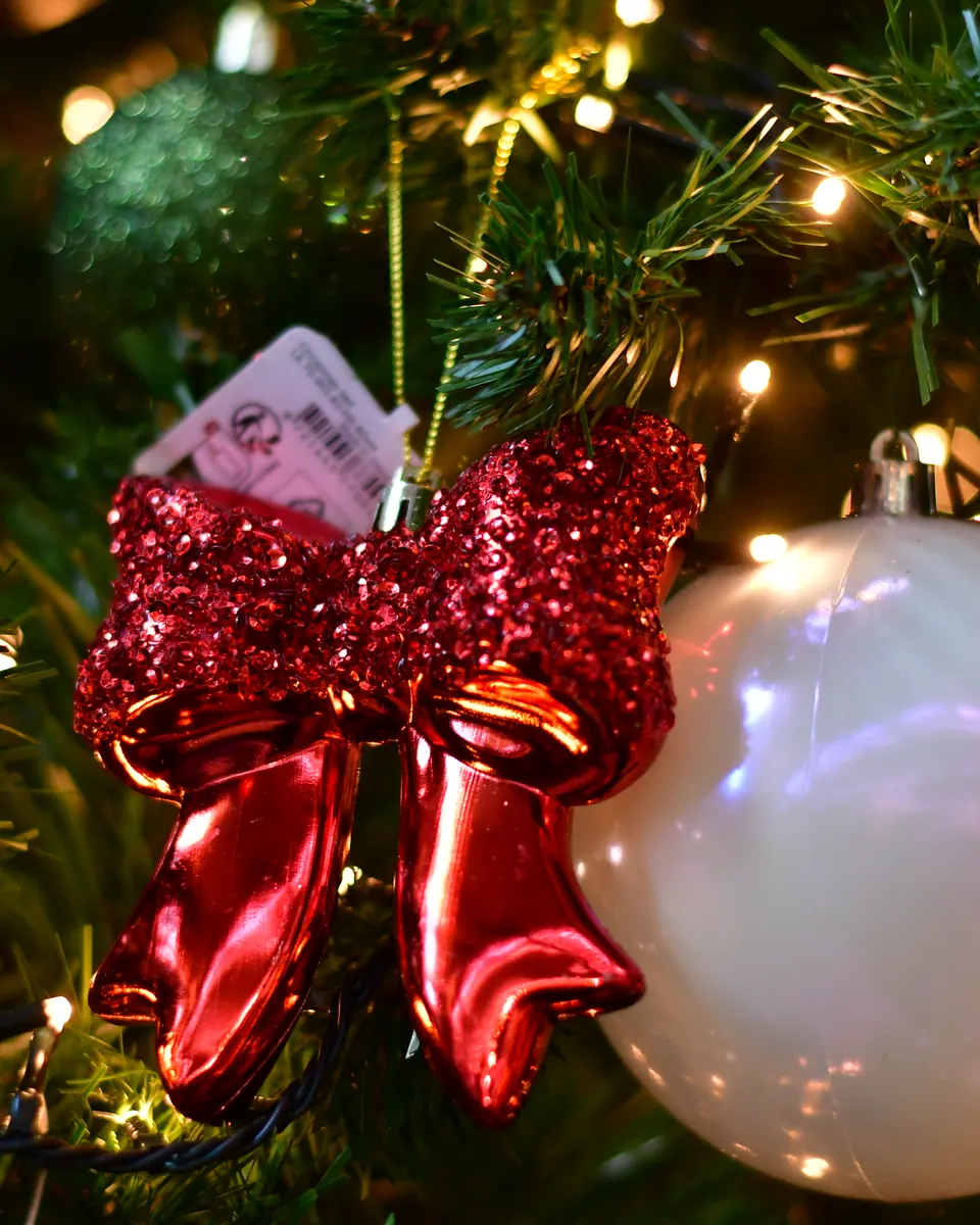 Rote Glitzerschleife mit Preisanhänger in einem geschmückten Baum