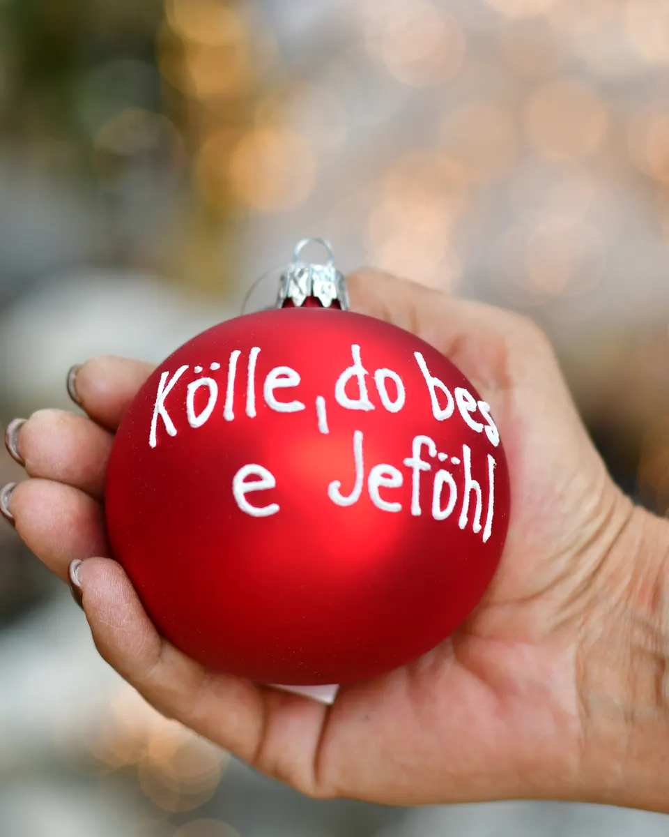 Rote Weihnachtskugel mit der Aufschrift Kölle, do bes e Jeföhl in einer Hand