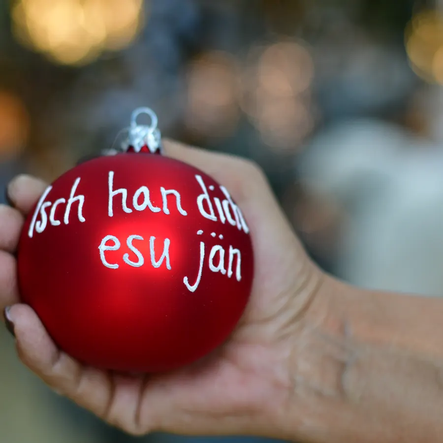 Rote Weihnachtskugel mit der Aufschrift Isch han dich esu jän in einer Hand
