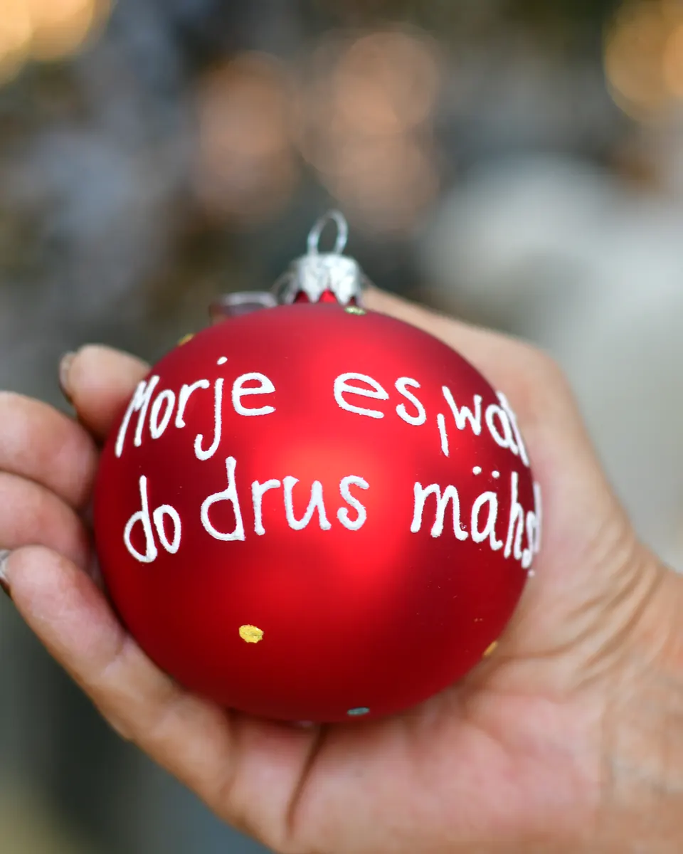 Rote Mottokugel mit kölschem Spruch in einer Hand