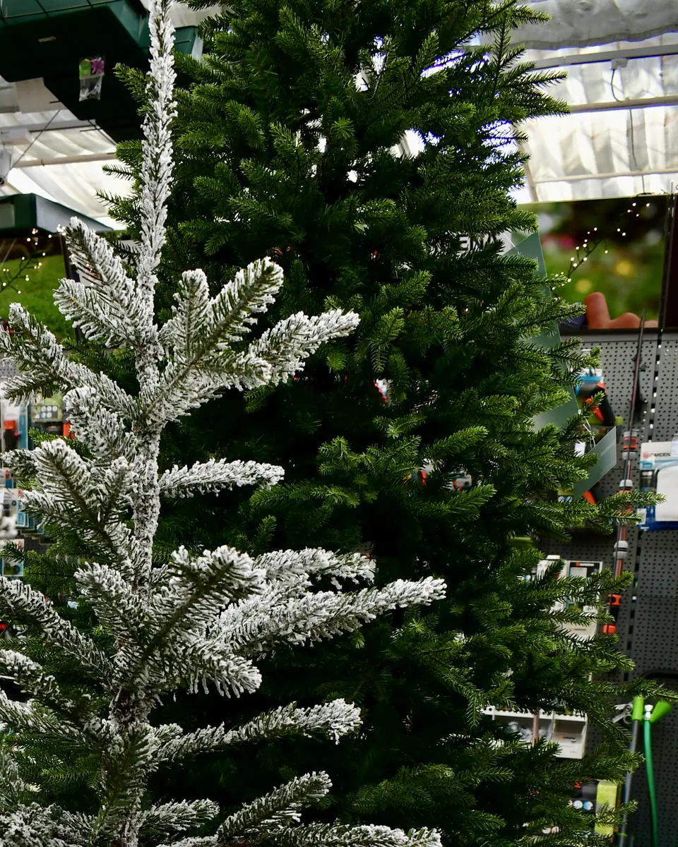 Beschneiter und grüner künstlicher Weihnachtsbaum nebeneinander