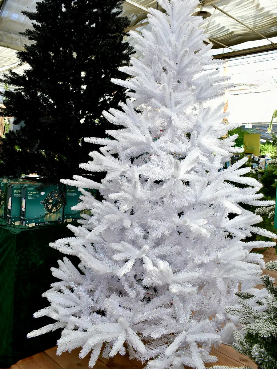 Weißer künstlicher Weihnachtsbaum vor einem schwarzen Kunstbaum