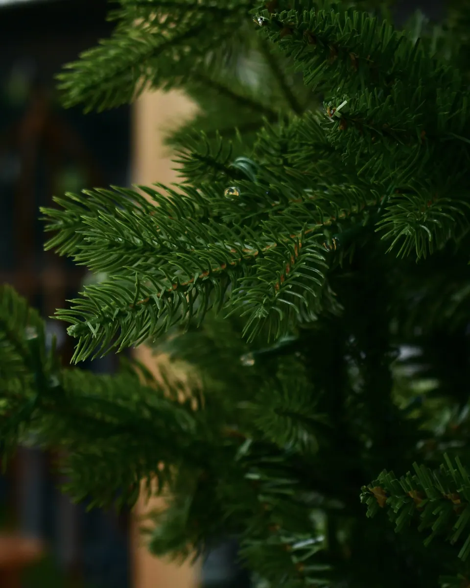 Nahaufnahme der Zweige eines künstlichen Weihnachtsbaums mit feinen grünen Nadeln