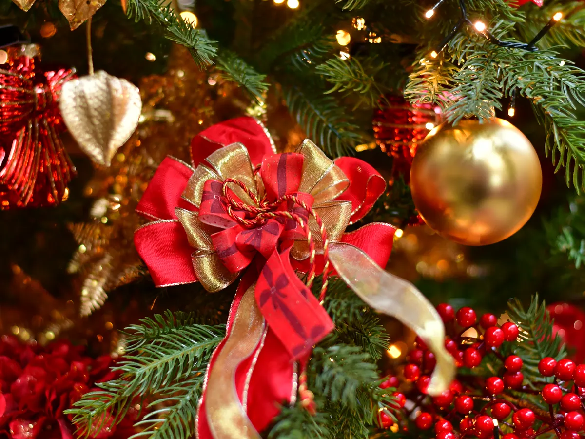 Schleife aus rotem und goldenem Band zwischen Christbaumkugeln