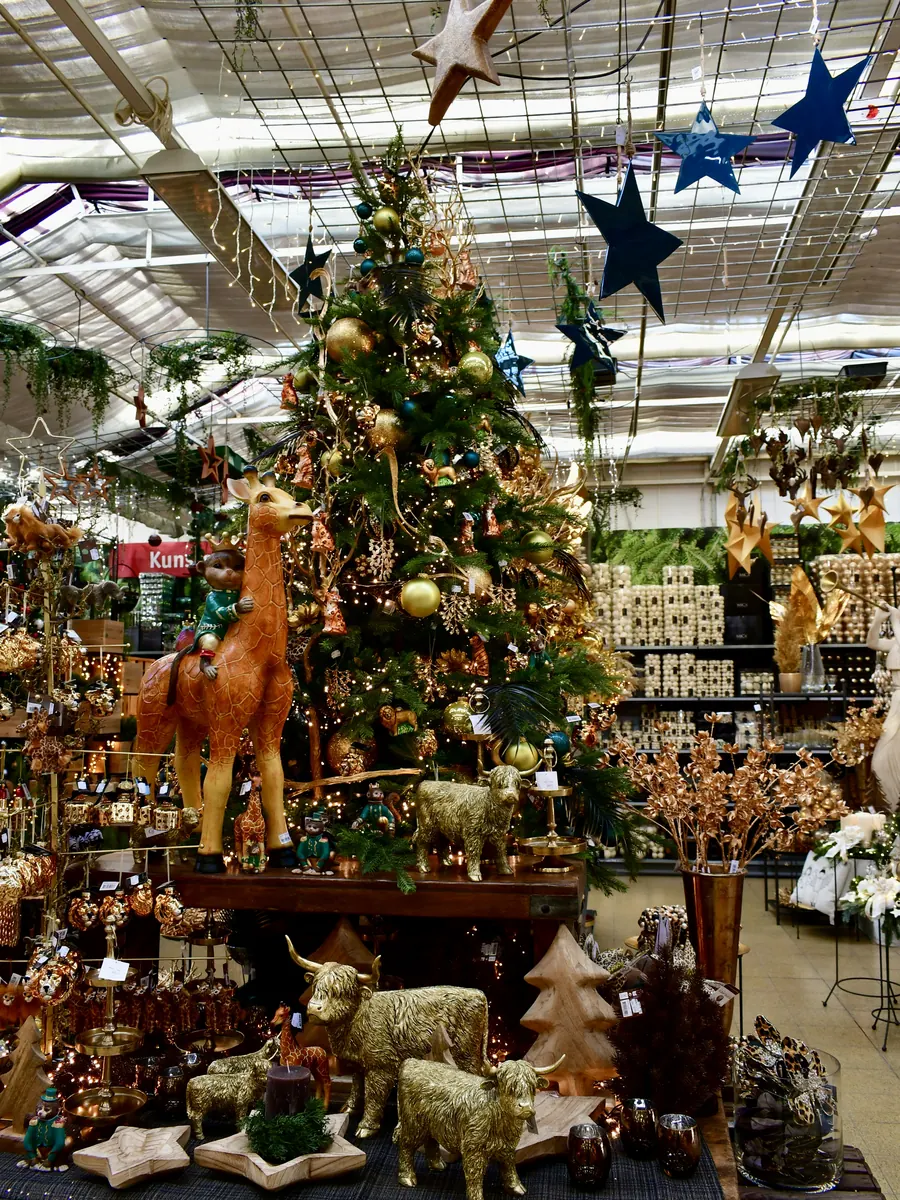 Themenbaum mit goldenen und petrolfarbenen Kugeln und Tierfiguren im Weihnachtsbazar
