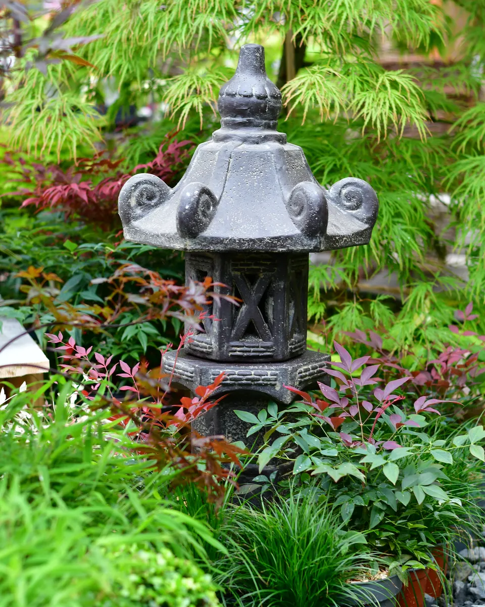 Steinlaterne zwischen Pflanzen im Gartenbereich